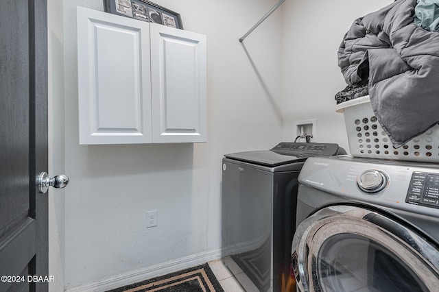 clothes washing area with cabinets, independent washer and dryer, and light tile patterned floors