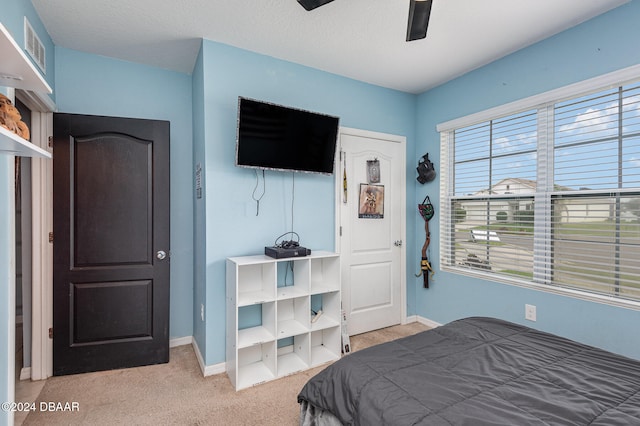 bedroom with a textured ceiling, light carpet, and ceiling fan