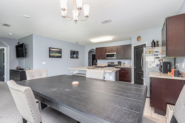 dining space with light tile patterned floors, a textured ceiling, sink, and an inviting chandelier