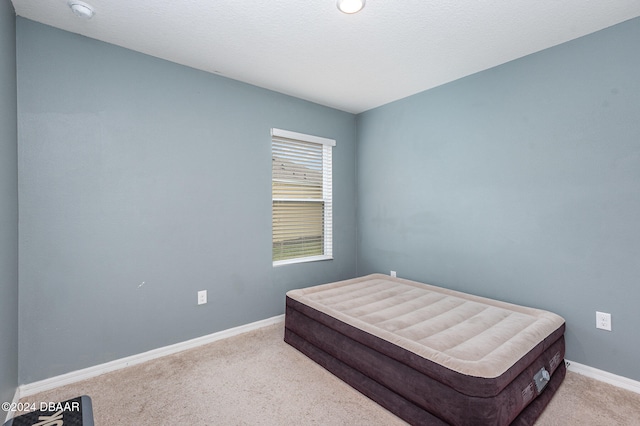 bedroom featuring light colored carpet and a textured ceiling