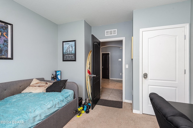 bedroom with a textured ceiling and light carpet