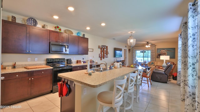 551 Armoyan Way, New Smyrna Beach, FL 32168 - kitchen featuring stainless steel microwave, electric range, light tile patterned flooring, light countertops, and a kitchen bar