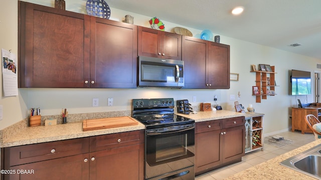 551 Armoyan Way, New Smyrna Beach, FL 32168 - kitchen with stainless steel microwave, range with electric cooktop, light tile patterned floors, and light countertops