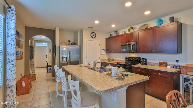 551 Armoyan Way, New Smyrna Beach, FL 32168 - kitchen with stainless steel appliances, light tile patterned floors, arched walkways, light countertops, and a kitchen breakfast bar