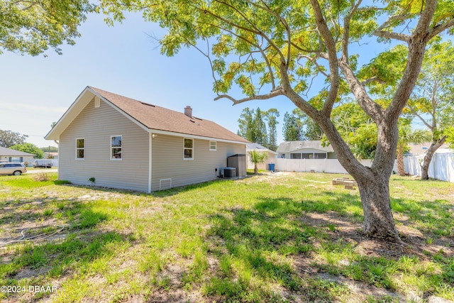 rear view of property with cooling unit and a lawn