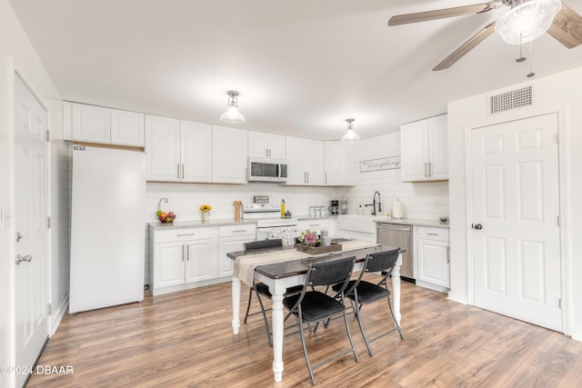 kitchen featuring white cabinets, white appliances, light wood-type flooring, and backsplash