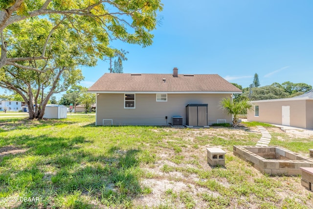 back of property with central AC and a yard