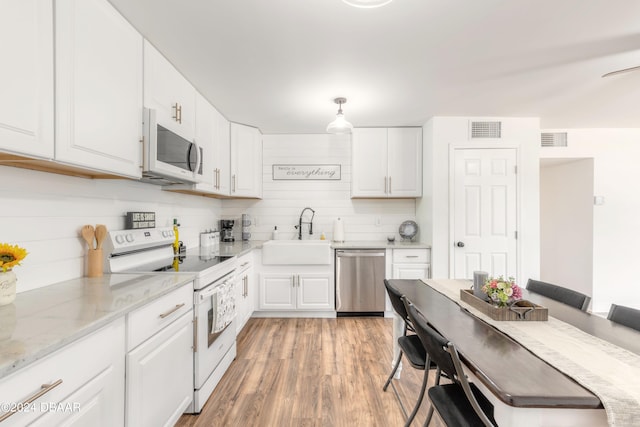 kitchen featuring white cabinetry, sink, light stone counters, white appliances, and light wood-type flooring