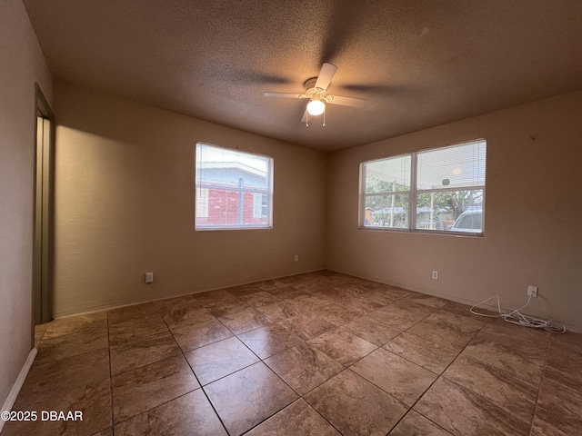 empty room featuring plenty of natural light, a textured ceiling, and a ceiling fan