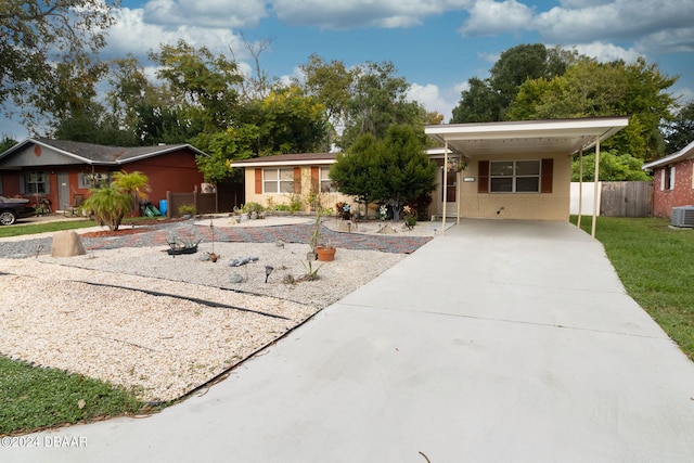 ranch-style home featuring central air condition unit, concrete driveway, fence, a carport, and a front lawn