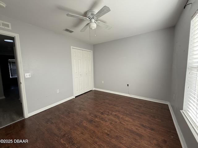 unfurnished bedroom featuring ceiling fan, dark hardwood / wood-style floors, and a closet