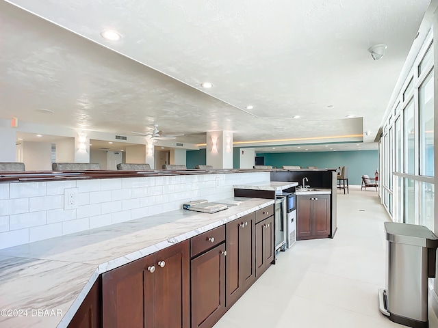 kitchen with dark brown cabinetry, a textured ceiling, tasteful backsplash, sink, and ceiling fan