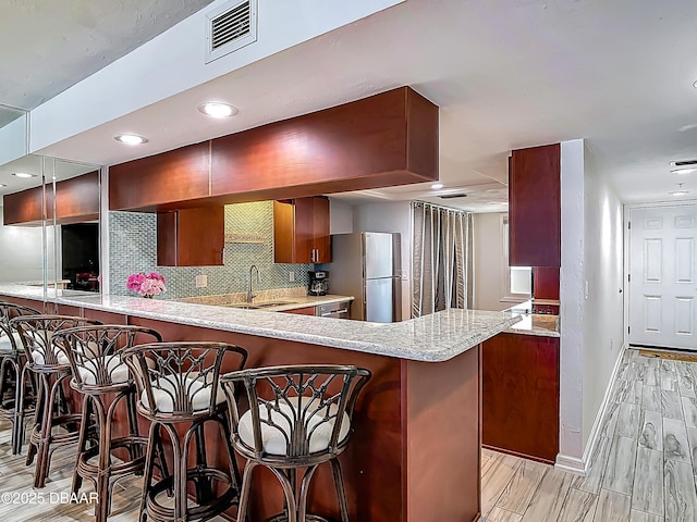 3333 S Atlantic Ave Unit 605, Daytona Beach, FL 32118 - kitchen featuring a sink, a peninsula, baseboards, decorative backsplash, and light wood-style flooring