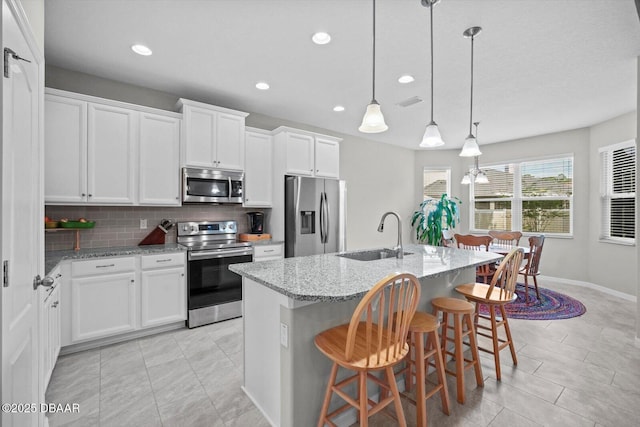 25 Egret Trl, Palm Coast, FL 32164 - kitchen featuring stainless steel appliances, light stone countertops, backsplash, an island with sink, and a kitchen breakfast bar