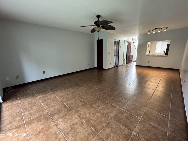 spare room featuring ceiling fan, baseboards, and dark tile patterned flooring