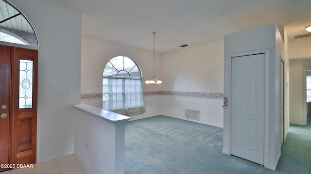 carpeted entryway featuring an inviting chandelier