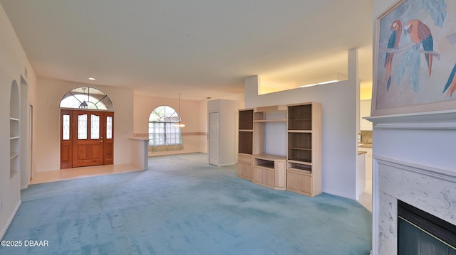 unfurnished living room with light carpet and a premium fireplace