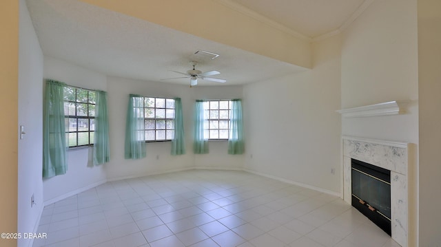 unfurnished living room with ceiling fan, light tile patterned floors, a premium fireplace, and ornamental molding