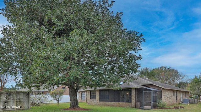 back of property with central AC, a sunroom, and a lawn