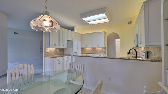 kitchen with white cabinets, kitchen peninsula, and decorative light fixtures