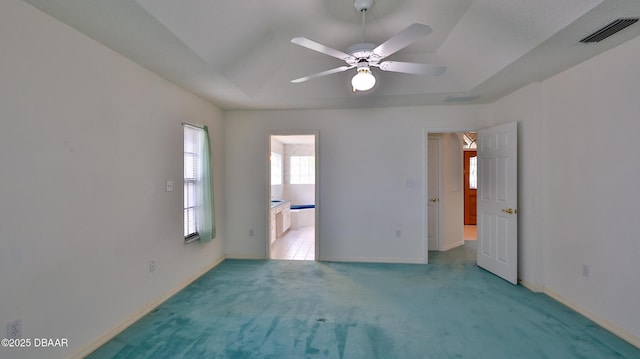 carpeted spare room with ceiling fan and a raised ceiling