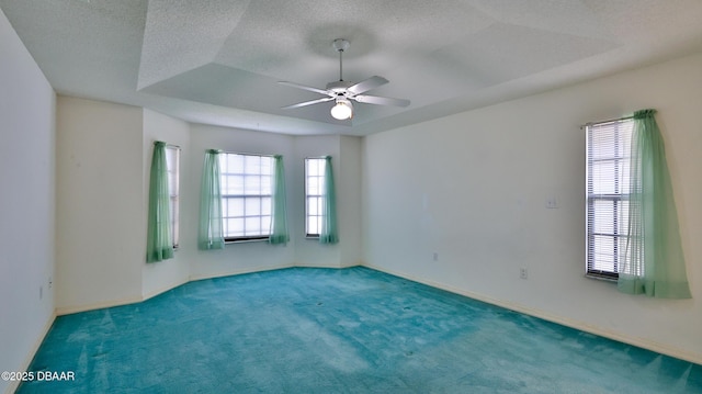 carpeted empty room featuring ceiling fan and a tray ceiling