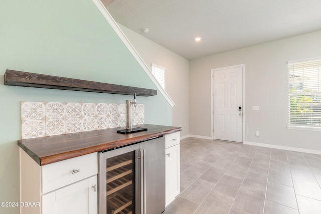 bar featuring white cabinetry, light tile patterned floors, beverage cooler, and wood counters