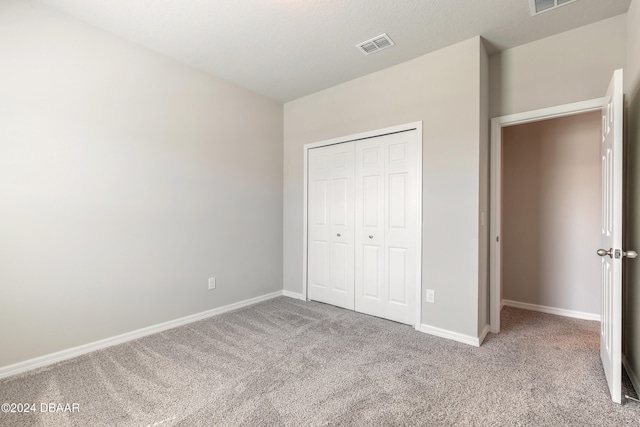 unfurnished bedroom with a closet and light colored carpet