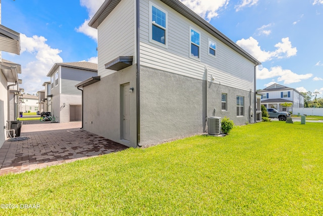 back of house with central air condition unit, a lawn, and a patio area