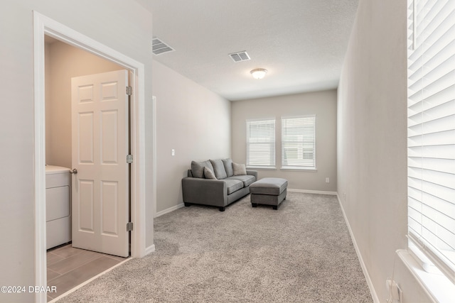 living room with a textured ceiling, washer / clothes dryer, and light carpet