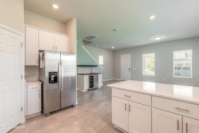 kitchen featuring white cabinets, beverage cooler, and stainless steel fridge