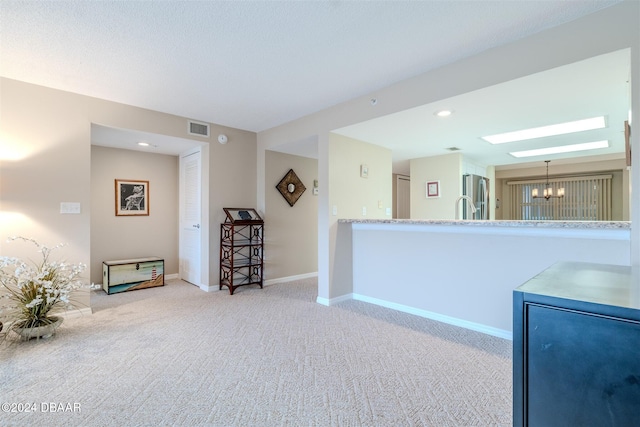 kitchen featuring an inviting chandelier, sink, hanging light fixtures, stainless steel fridge, and light colored carpet