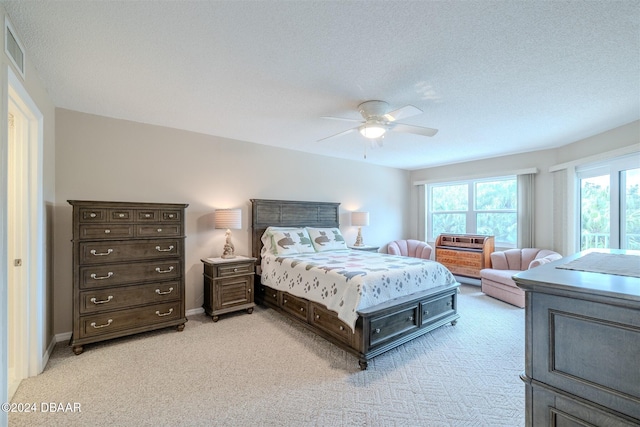 bedroom with a textured ceiling, ceiling fan, and light carpet