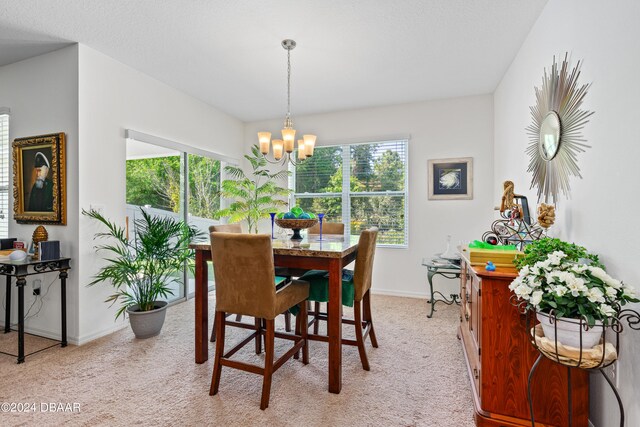 carpeted dining area with a chandelier