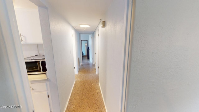 hallway with light speckled floor and baseboards