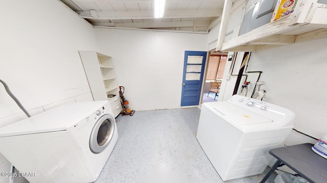 laundry area featuring laundry area, concrete block wall, and washer and clothes dryer