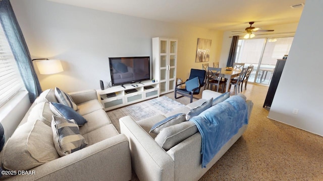 living area with visible vents, a ceiling fan, and speckled floor