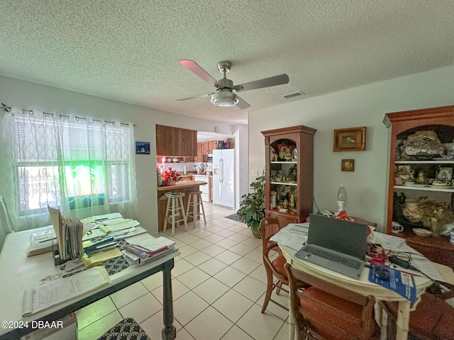 tiled dining area with a textured ceiling and ceiling fan