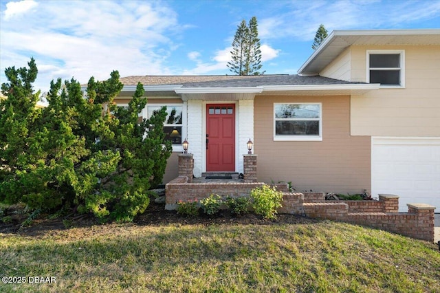 view of exterior entry with a garage and a lawn