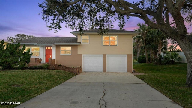 tri-level home with a garage and a lawn