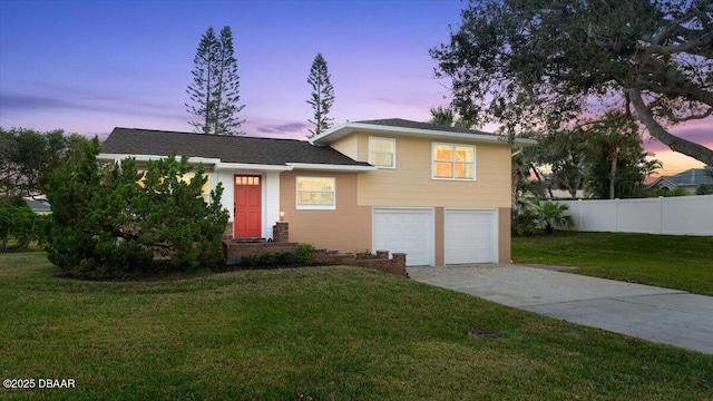 tri-level home with a garage and a lawn