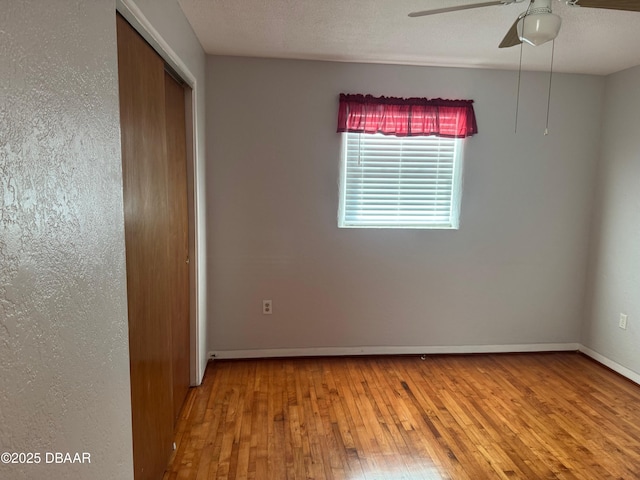 unfurnished bedroom featuring ceiling fan, a closet, and hardwood / wood-style flooring