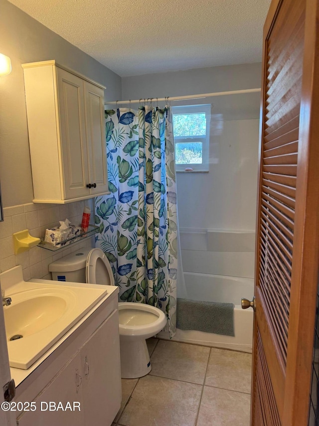 full bathroom featuring tile patterned floors, vanity, a textured ceiling, shower / tub combo with curtain, and toilet