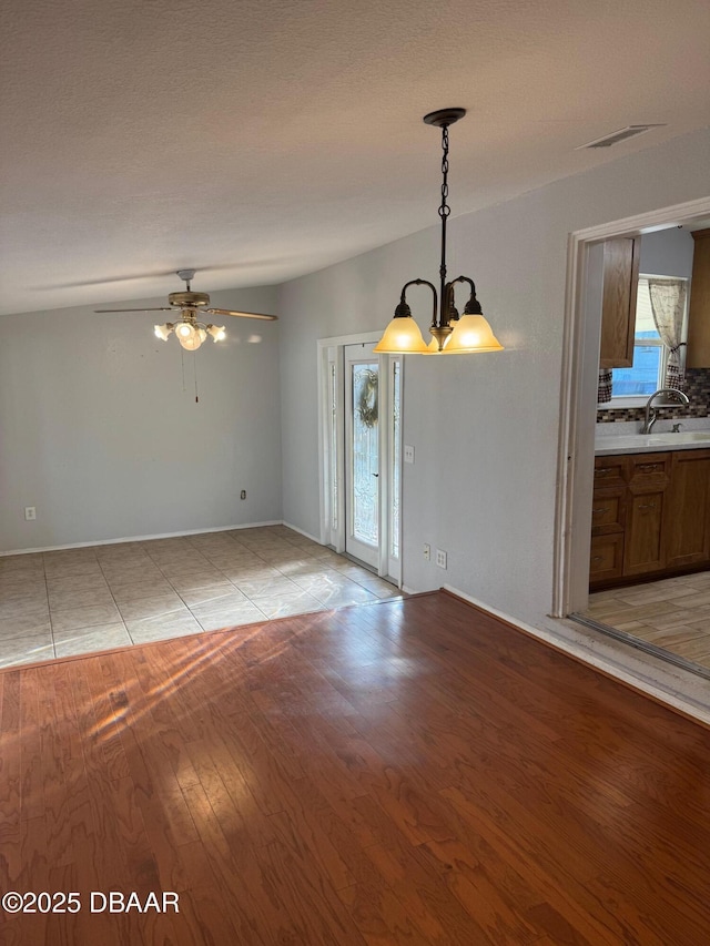 unfurnished room featuring ceiling fan with notable chandelier, light wood-type flooring, and sink