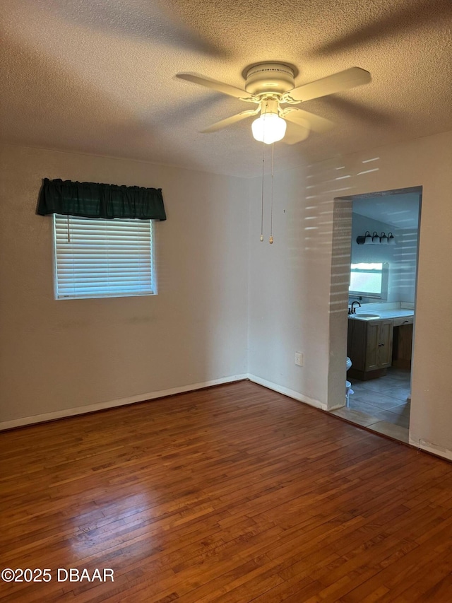 spare room with hardwood / wood-style floors, ceiling fan, and a textured ceiling