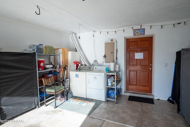 washroom featuring electric panel, washing machine and dryer, and dark tile patterned flooring