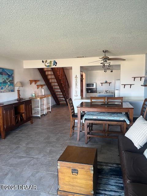 living area with a textured ceiling, stairway, and a ceiling fan