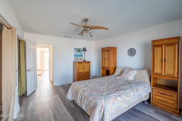 bedroom featuring ceiling fan, wood-type flooring, and a textured ceiling