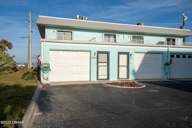 townhome / multi-family property featuring a balcony, a garage, and stucco siding