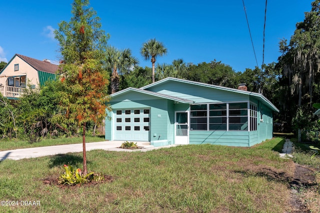 view of front of home featuring a garage, a front lawn, and a sunroom